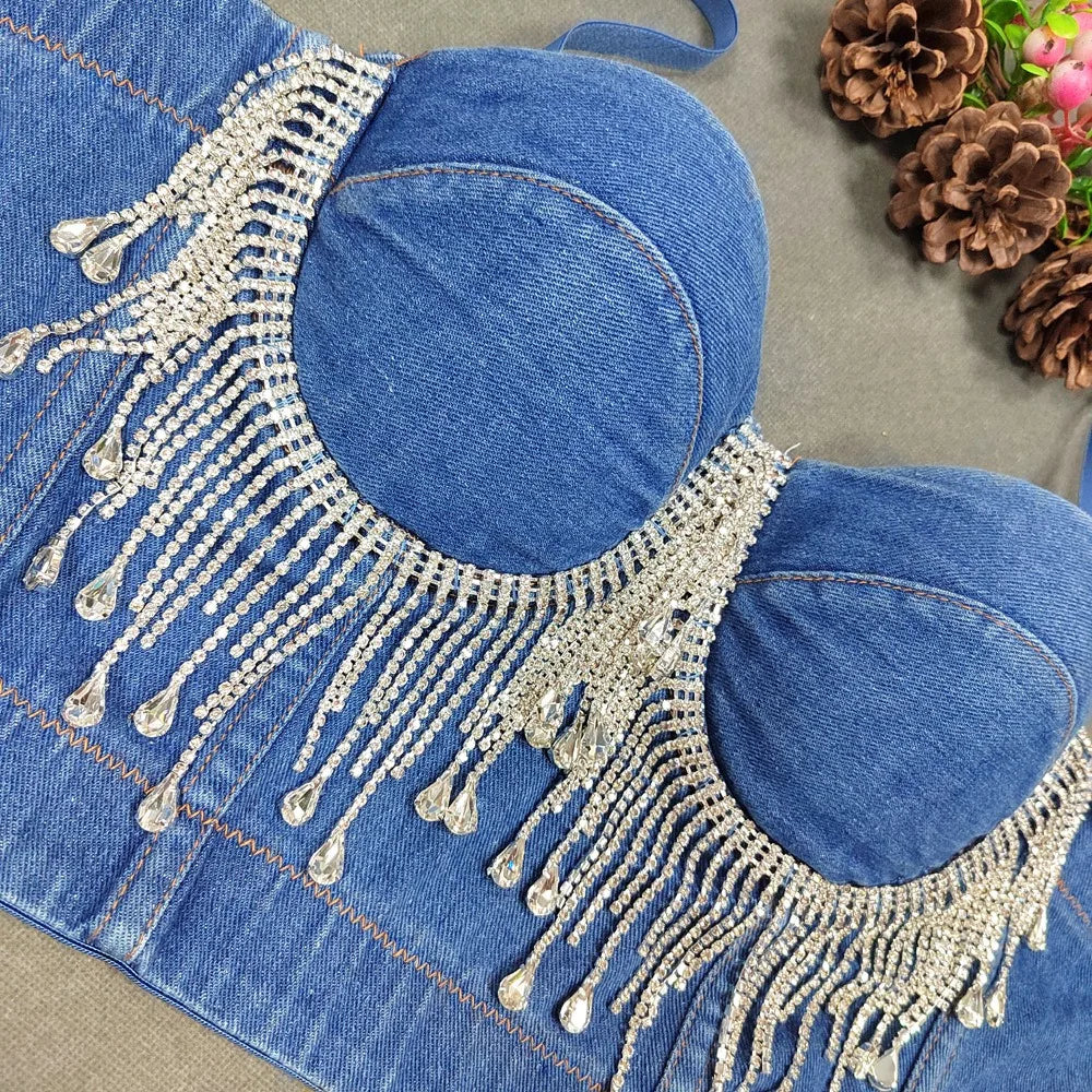 A denim corset with hanging rhinestones strikes a bold balance between rugged edge and high-glam allure. The structured denim hugs the body, giving it that classic, sculpted silhouette, while the cascading rhinestones add mov
