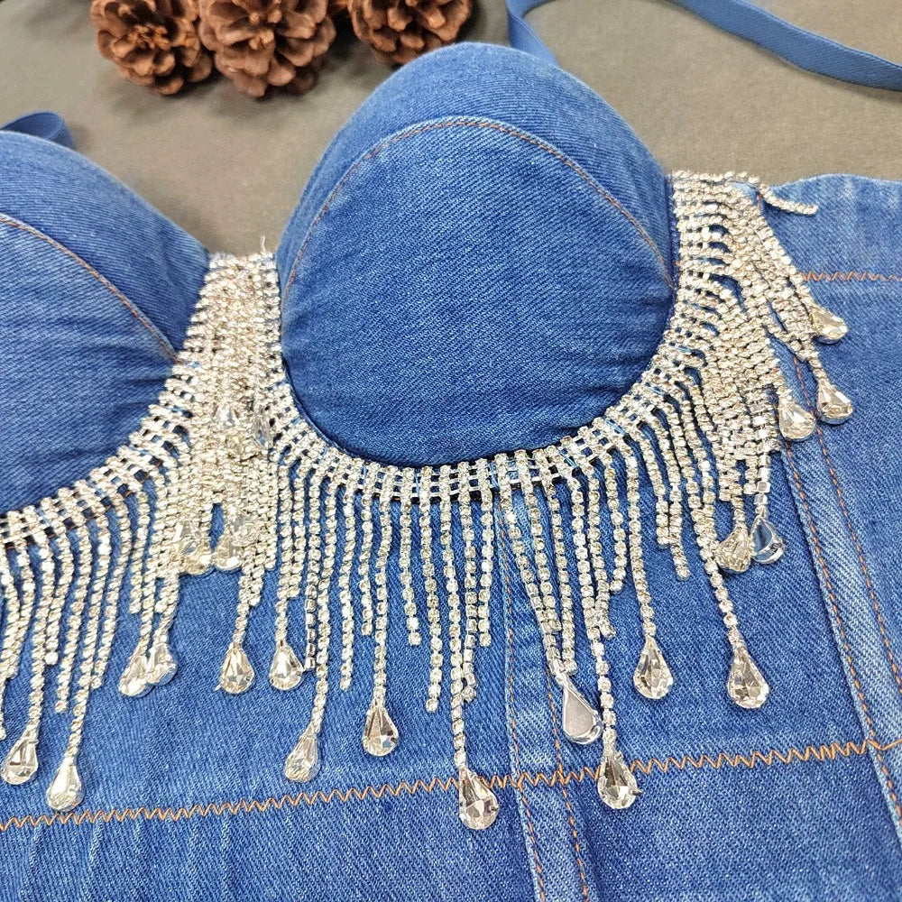 A denim corset with hanging rhinestones strikes a bold balance between rugged edge and high-glam allure. The structured denim hugs the body, giving it that classic, sculpted silhouette, while the cascading rhinestones add mov