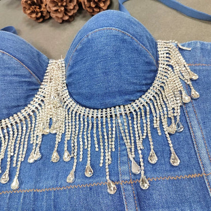 A denim corset with hanging rhinestones strikes a bold balance between rugged edge and high-glam allure. The structured denim hugs the body, giving it that classic, sculpted silhouette, while the cascading rhinestones add mov