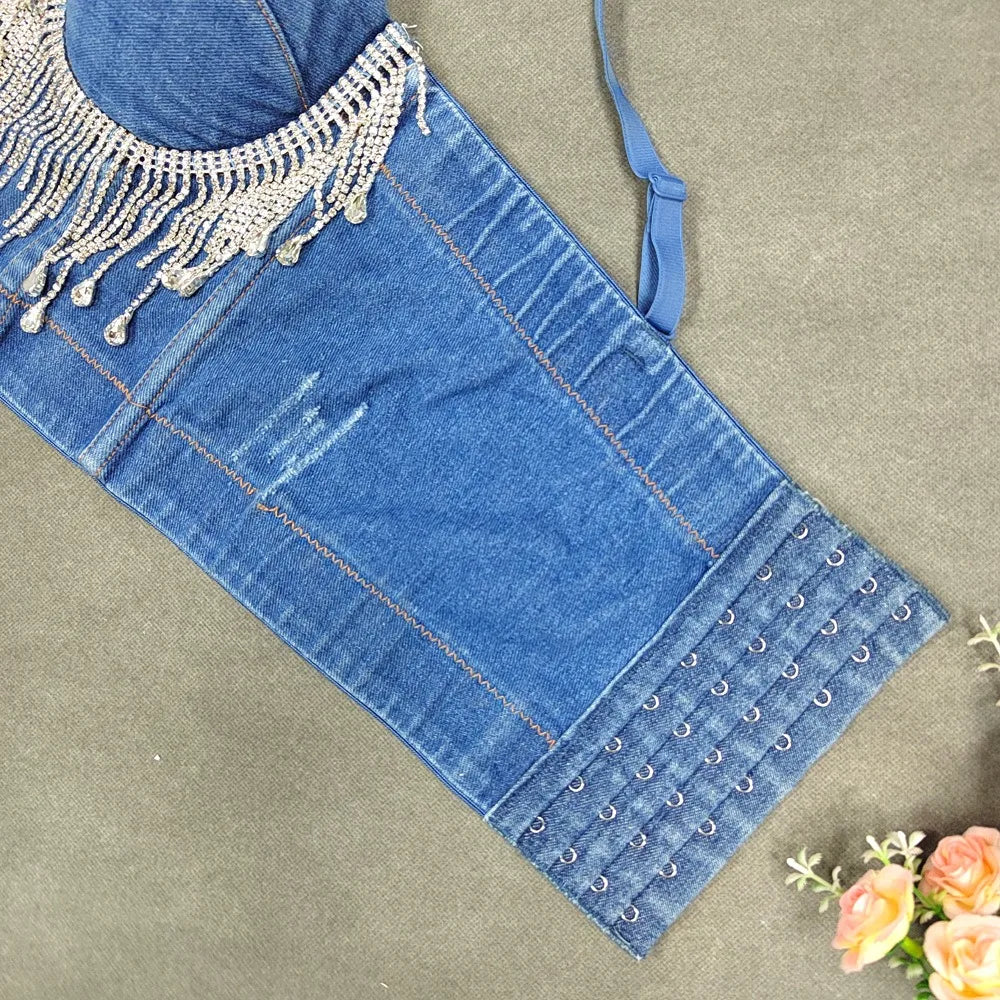 A denim corset with hanging rhinestones strikes a bold balance between rugged edge and high-glam allure. The structured denim hugs the body, giving it that classic, sculpted silhouette, while the cascading rhinestones add mov