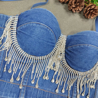A denim corset with hanging rhinestones strikes a bold balance between rugged edge and high-glam allure. The structured denim hugs the body, giving it that classic, sculpted silhouette, while the cascading rhinestones add mov