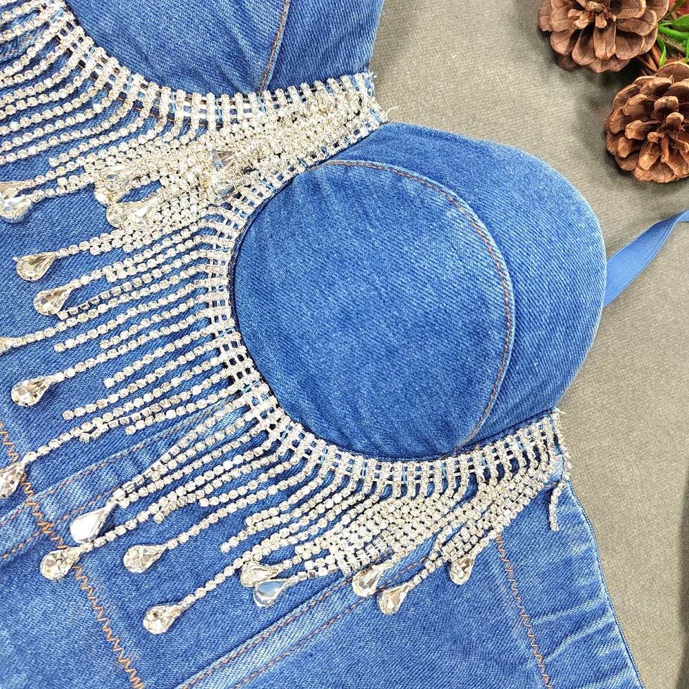 A denim corset with hanging rhinestones strikes a bold balance between rugged edge and high-glam allure. The structured denim hugs the body, giving it that classic, sculpted silhouette, while the cascading rhinestones add mov