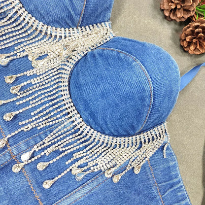 A denim corset with hanging rhinestones strikes a bold balance between rugged edge and high-glam allure. The structured denim hugs the body, giving it that classic, sculpted silhouette, while the cascading rhinestones add mov